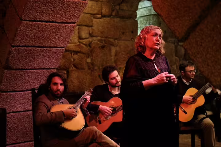 A soulful Fado singer performs with guitarists in a rustic Porto cellar, perfect for an enchanting moonlight walk and dinner experience.