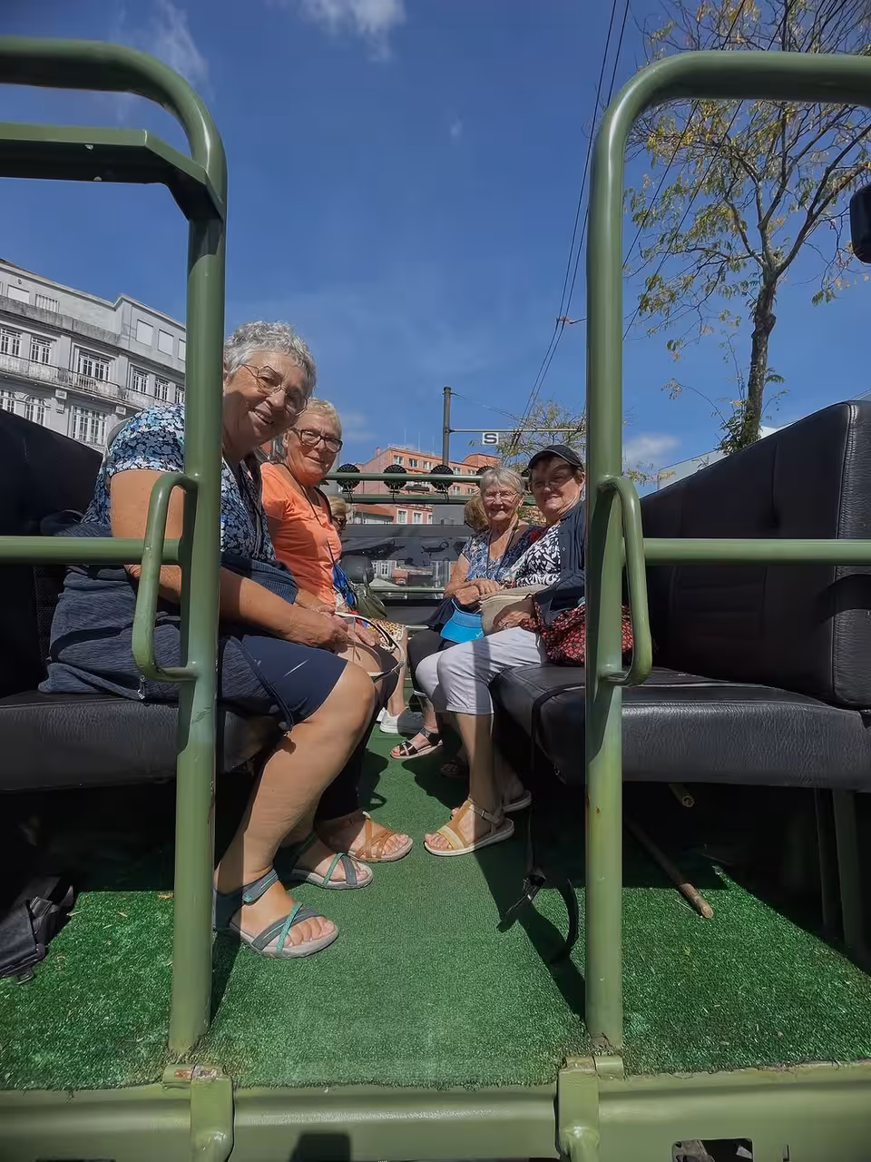 Guests riding an open-top bus in Porto on the Porto, Gaia and Douro tour under a clear blue sky