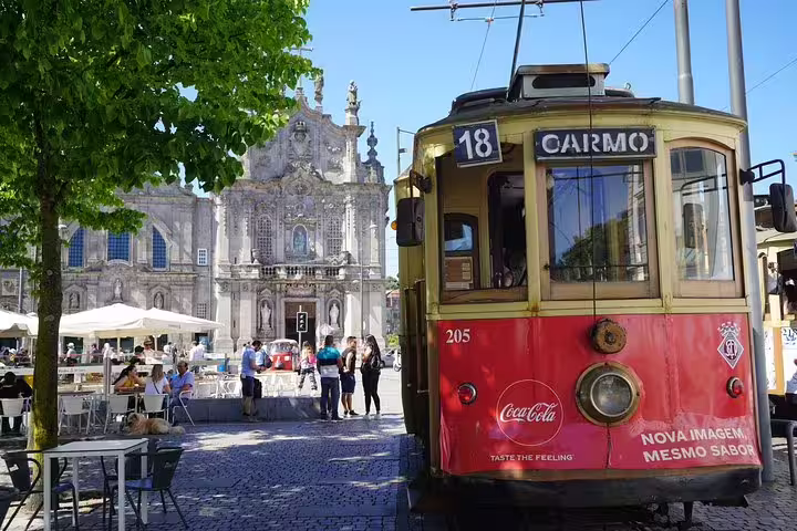 Historic tram in Porto's scenic Carmo district with people enjoying outdoor cafes, ideal for Vicentine Coast to Porto transfers.
