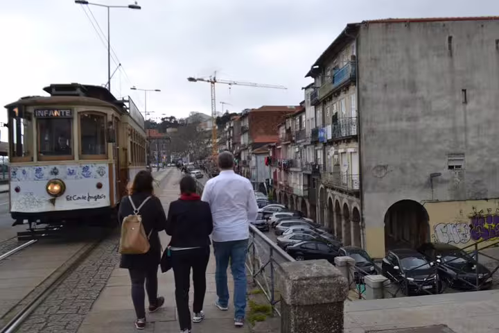 Tourists walk along a tramline in Porto's Jewish Heritage area, experiencing local culture and historic architecture.