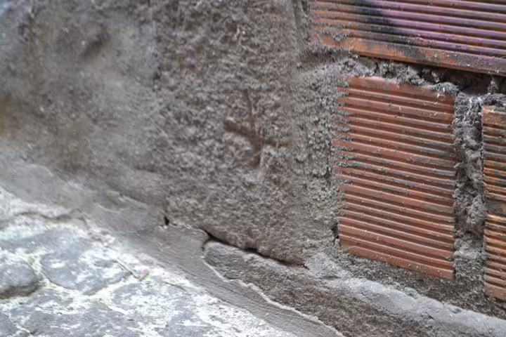 Close-up of a historic wall in Porto's Jewish quarter, showcasing vintage stonework and a cross marking.