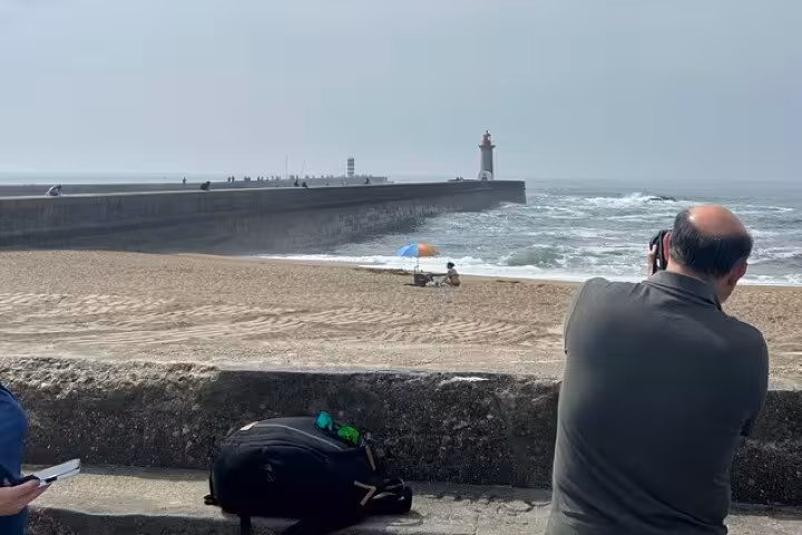 Traveler photographing Porto lighthouse by the Atlantic, part of half-day Porto & beach-side small-group tour tastings