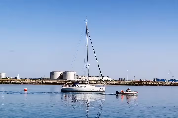 Sailboat and motorboat on calm waters during a sunny Porto to Lisbon private tour, highlighting customizable travel experiences.