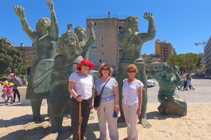 Tourists explore a striking modern sculpture in a vibrant Portuguese city, a must-see stop on a Porto to Lisbon transfer.