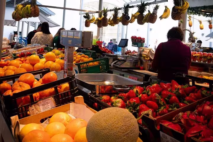 Vibrant Porto market scene with fresh oranges, strawberries, and tropical fruits, perfect for a local food tour experience.