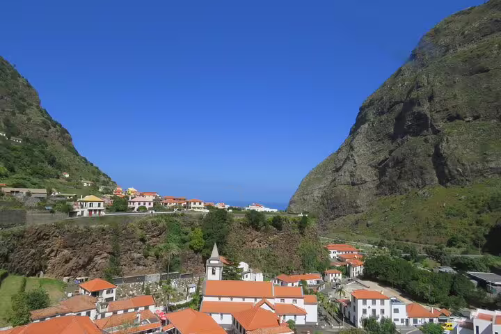 Scenic view of Porto Moniz village nestled between lush cliffs and the Atlantic Ocean, perfect for a 4x4 Jeep adventure tour.