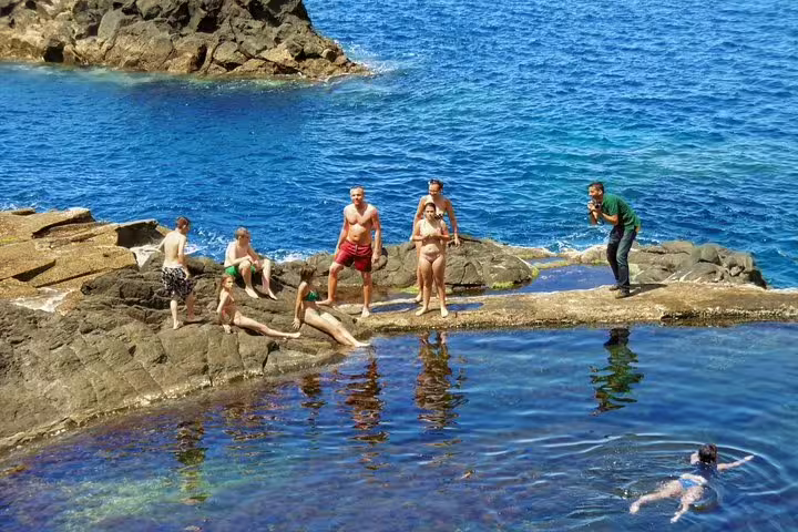 Visitors enjoy crystal-clear natural pools along the scenic Porto Moniz coastline on the Enchanted Terraces 4x4 tour.