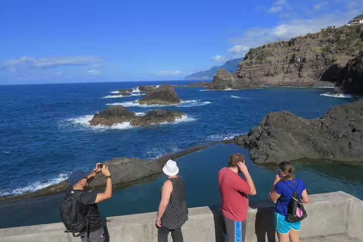 Travelers admire the stunning natural pools and rugged coastline of Porto Moniz on a full-day local guided tour.