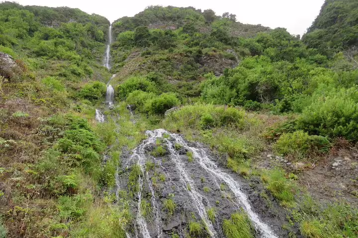 Lush green hills with cascading waterfalls in Porto Moniz, perfect for a full-day nature tour with local guides.