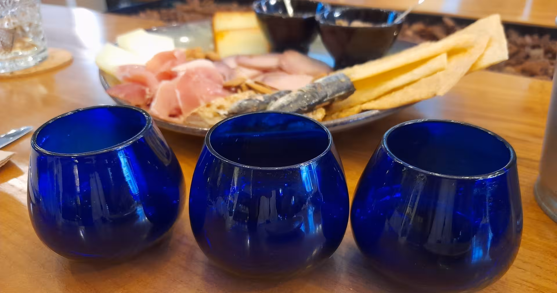 Three blue tasting glasses with Portuguese charcuterie board at a Porto olive oil tasting tour