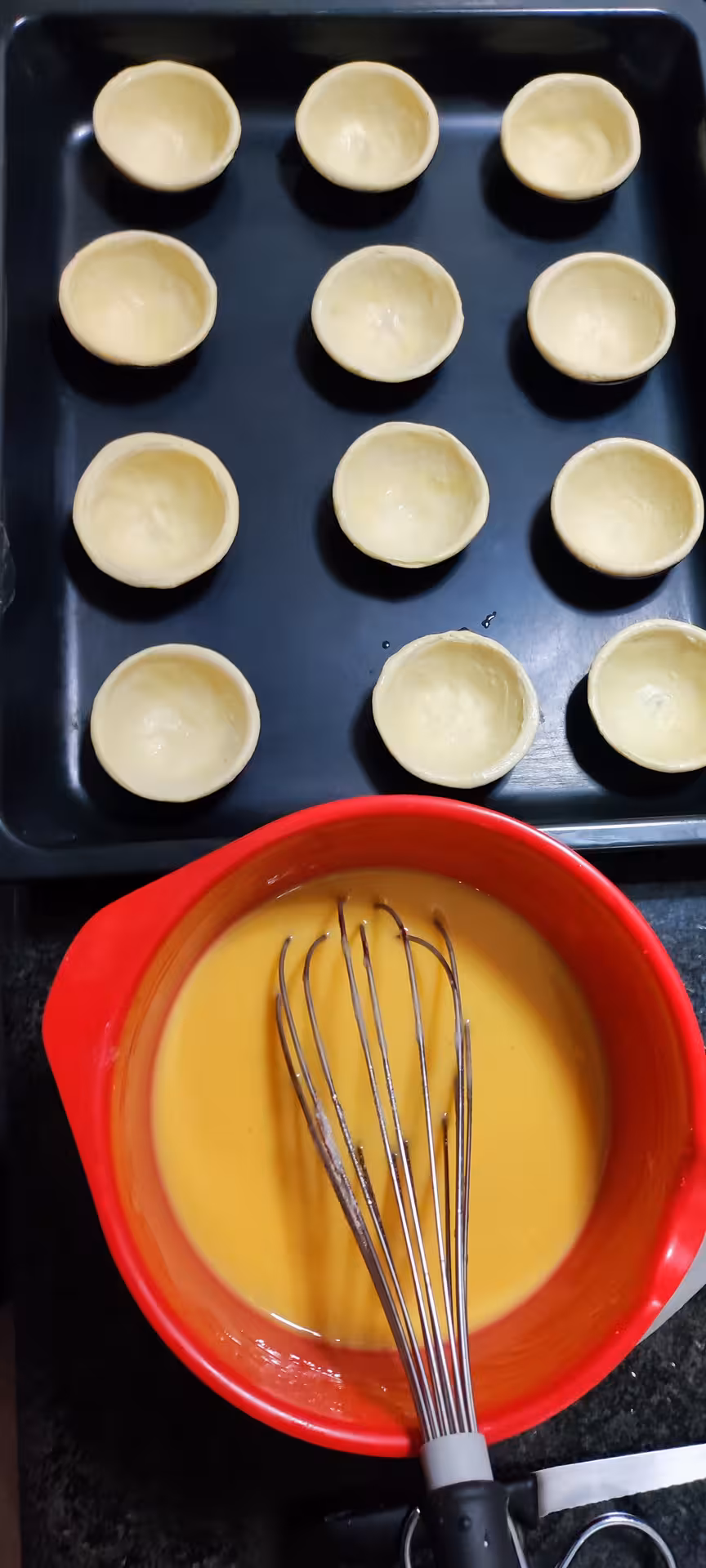 Preparation of pastel de nata with custard mixture and pastry shells ready for baking at Porto cooking class.