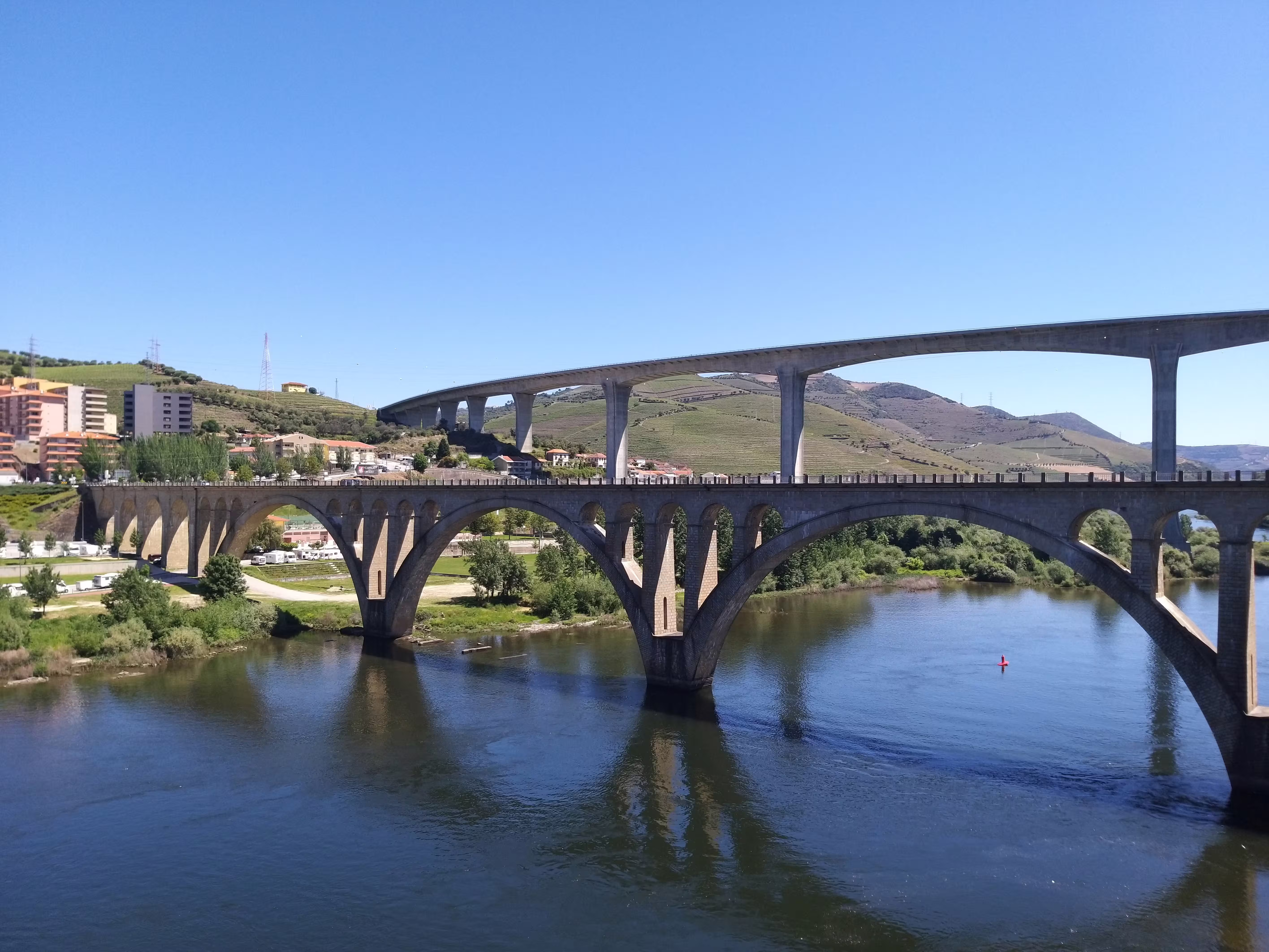 Scenic view of the Peso da Régua bridge over the Douro River, highlighting lush landscapes on a private car transfer from Porto.