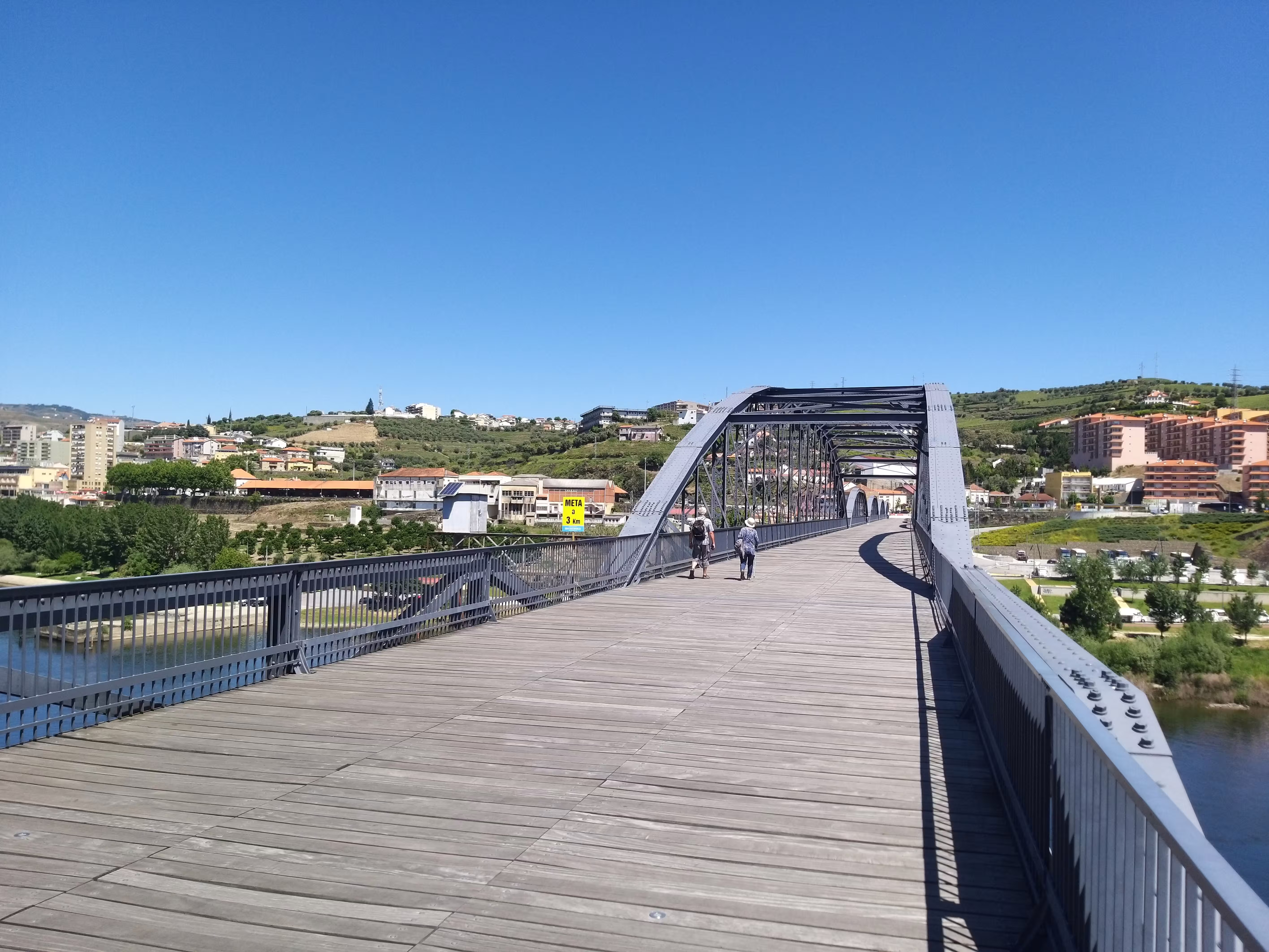 Wooden pedestrian bridge with scenic views of Peso da Régua, highlighting the tranquility of private car transfers from Porto.