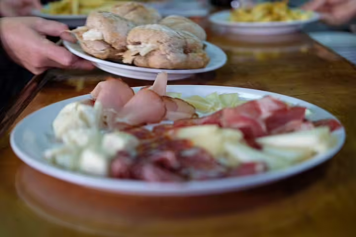 Assorted Portuguese charcuterie and fresh bread on a wooden table, showcasing authentic Porto culinary traditions.