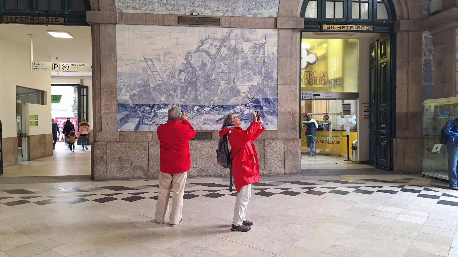 Visitors admire iconic blue tile murals at São Bento Station on a Porto private morning tour, capturing local history and culture.