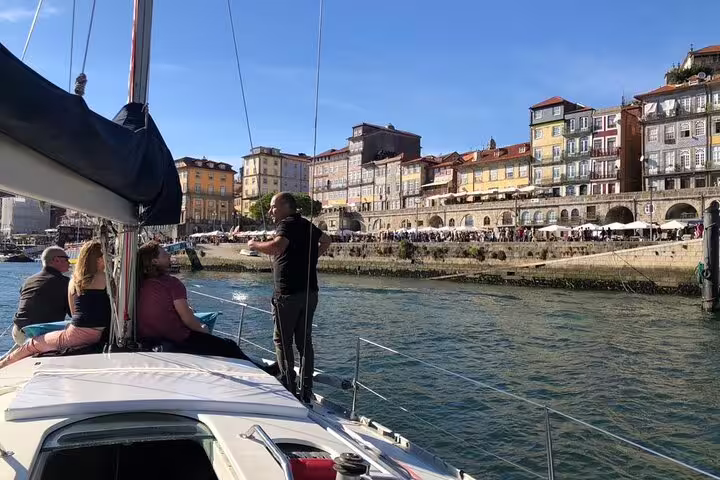 Tourists enjoying a private yacht tour along the scenic Douro River with vibrant Porto buildings in the background.