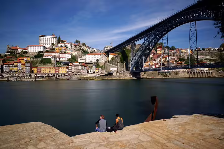 Two people enjoying the view of Porto's historic Ribeira and Dom Luís I Bridge on a private tour from Lisbon.