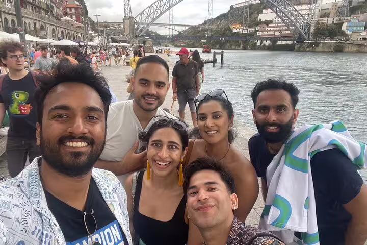 Group selfie at Ribeira waterfront near Dom Luís I Bridge during a Porto scavenger hunt and sights self-guided tour