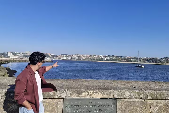 Tourist pointing at scenic Porto river view from a stone wall, perfect for a private city tour with coastal vistas.