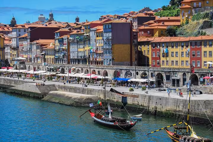 Colorful riverside view of Porto with traditional boats and historic buildings, perfect for a guided tour from Madrid.
