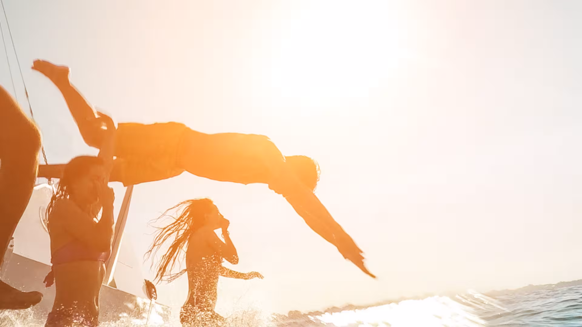 Group of people joyfully diving into the sea from a boat, enjoying sunny weather on a Porto Rotondo tour.