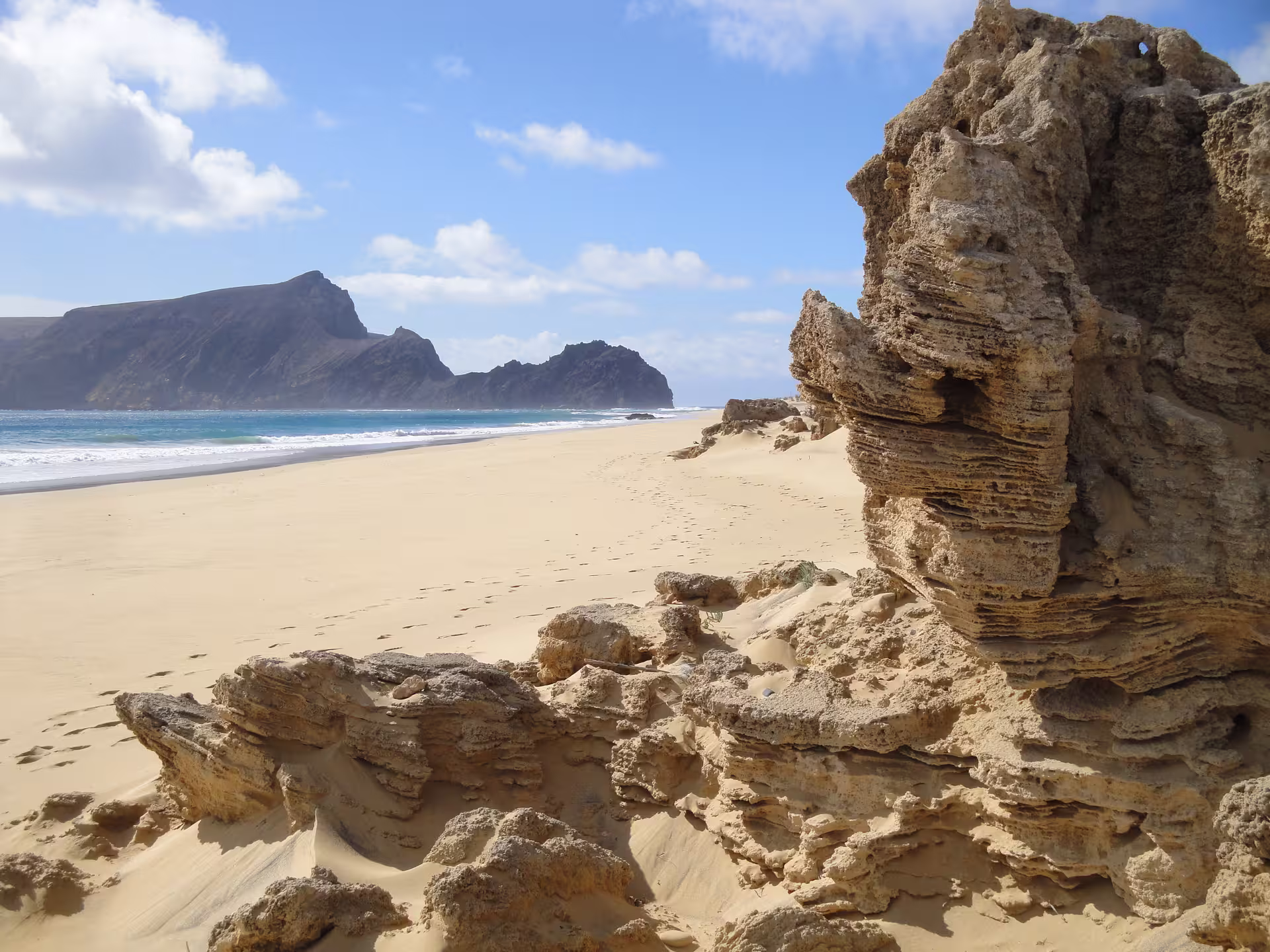 Golden sands and rugged cliffs of Porto Santo beach under a blue sky, perfect for a 1-day land adventure experience.