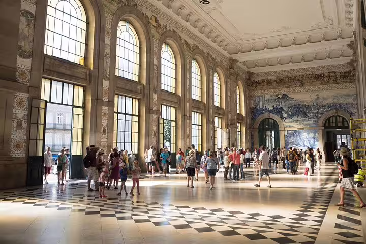 Tourists explore the stunning São Bento Railway Station in Porto, renowned for its intricate azulejo tile artwork.