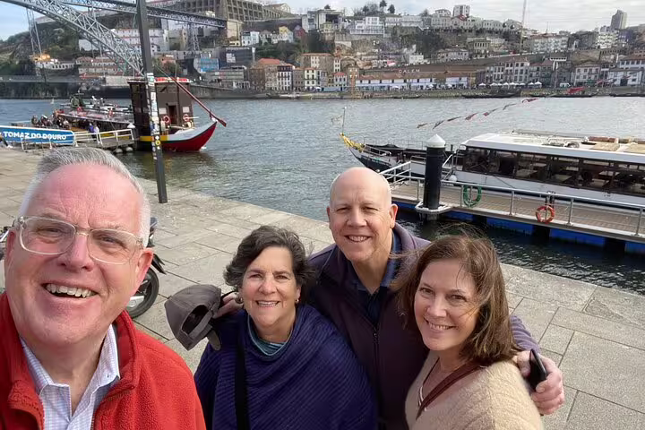 Group selfie at Douro River quay with rabelo boat and Porto skyline, Porto scavenger hunt self-guided tour