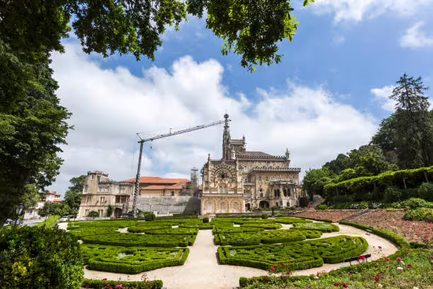 Lush garden and historic architecture of a palace in Tomar under a partly cloudy sky, perfect for private tours.