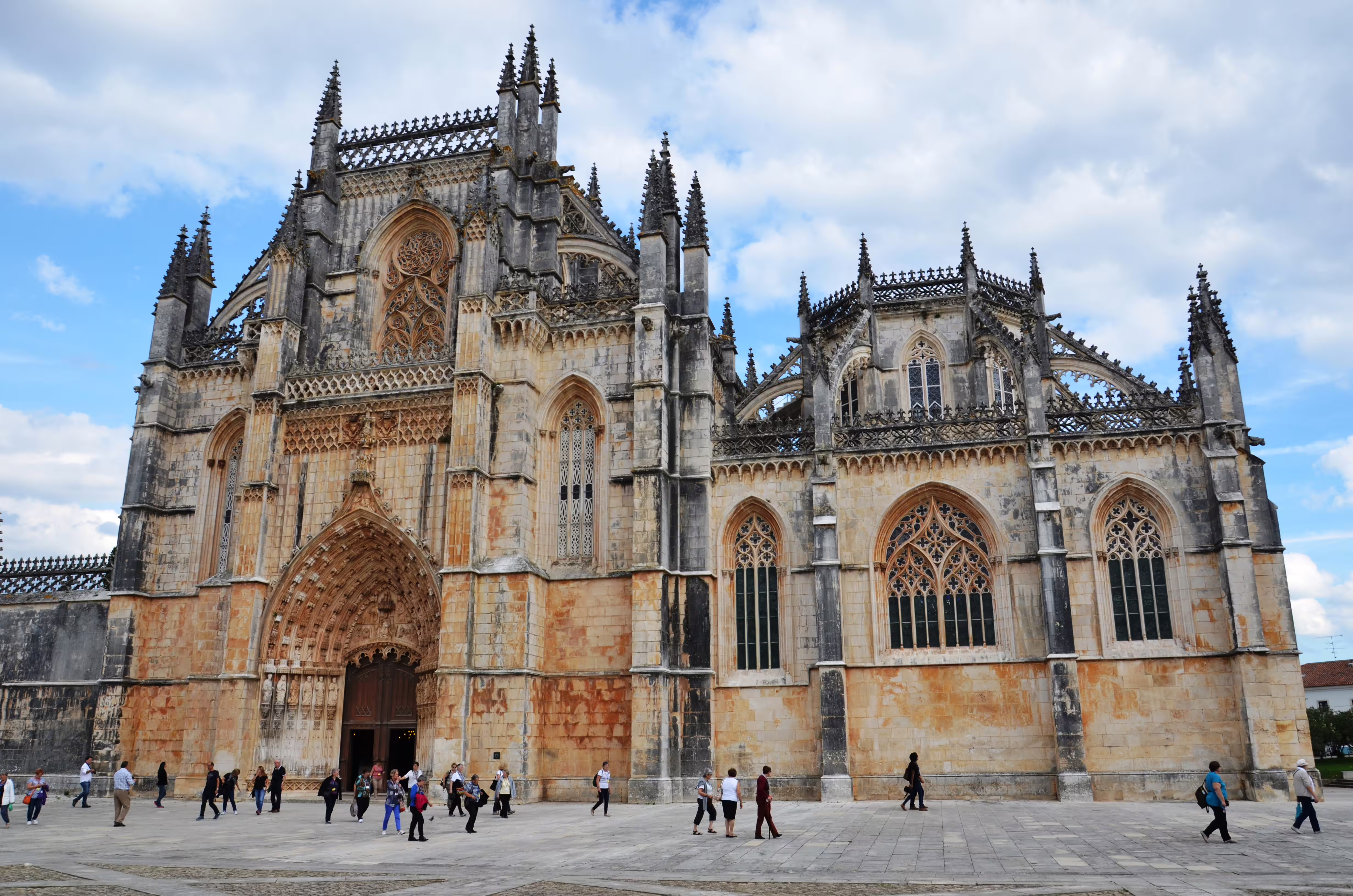 Batalha Monastery's Gothic architecture with visitors walking near the grand entrance.