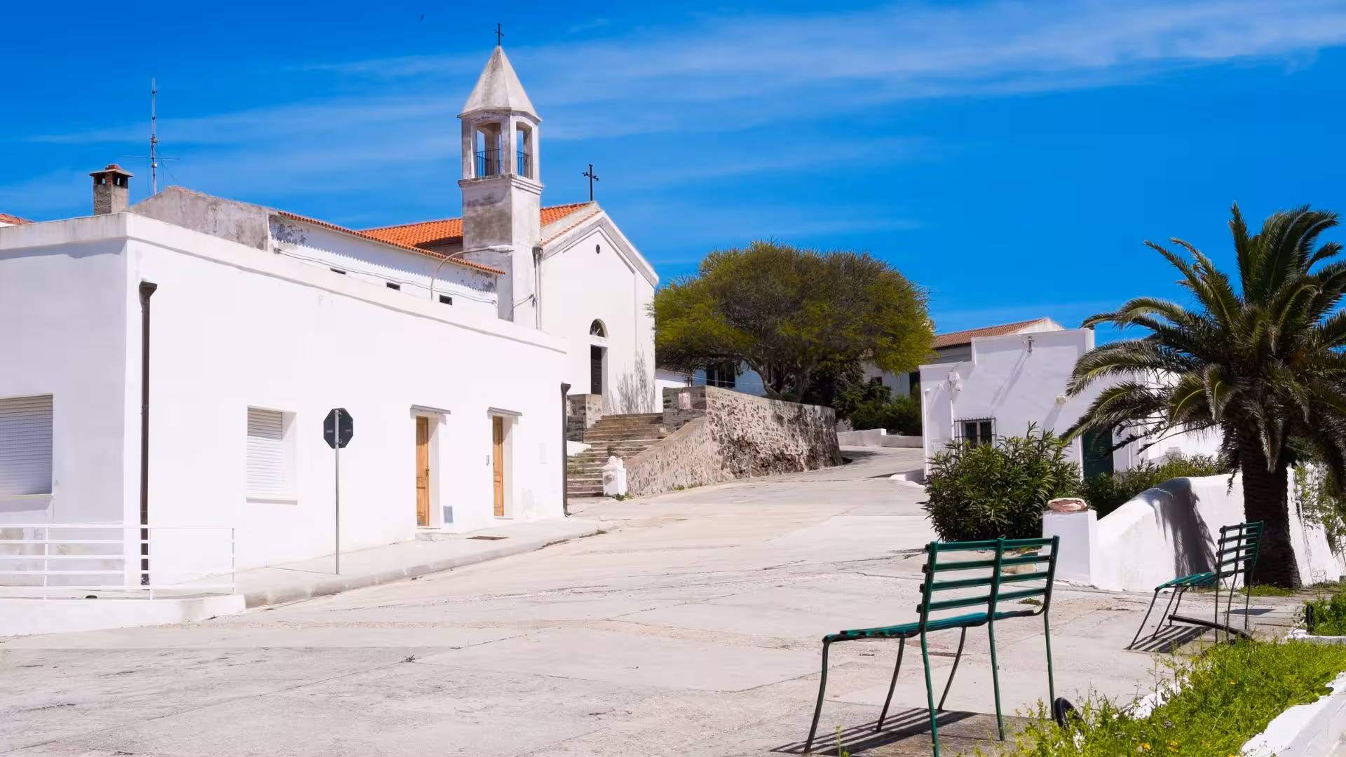Charming white church and buildings in a tranquil Asinara Island village, ideal stop on Porto Torres minivan tour.