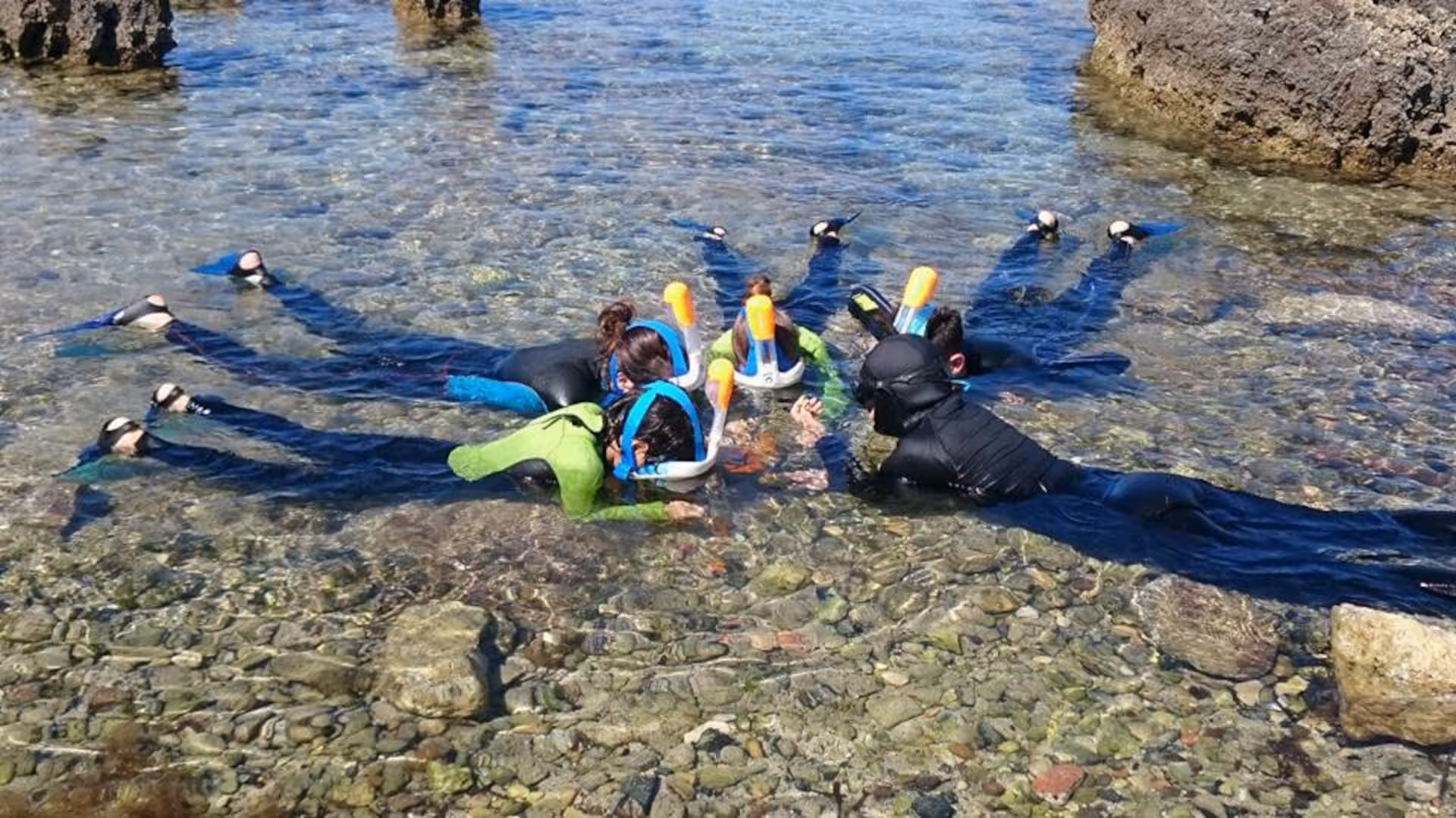Group snorkeling in the clear waters of Porto Torres' Bay of Balai, exploring vibrant marine life.