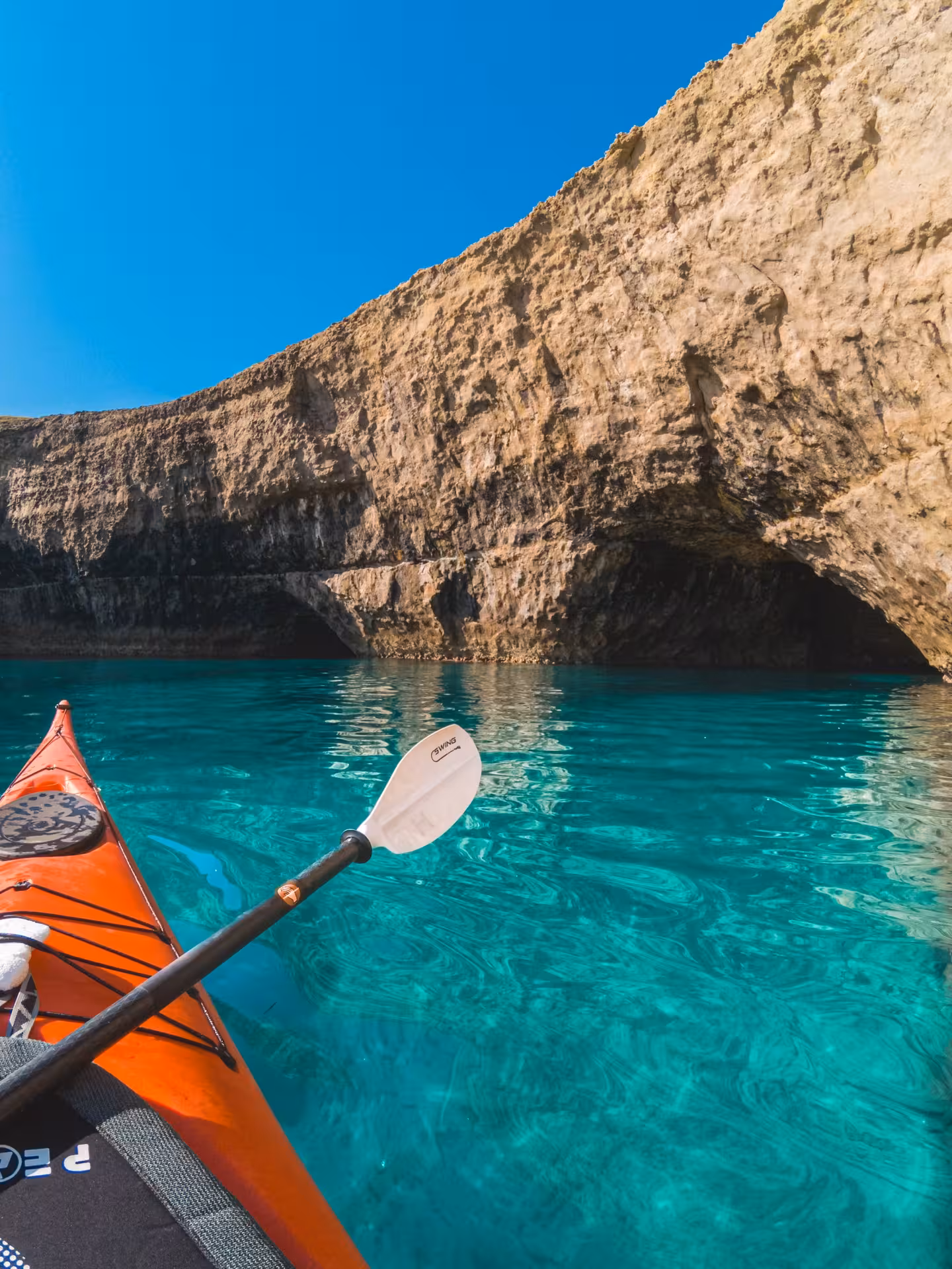 Explore stunning sea caves on a kayak excursion in Porto Torres, gliding through crystal-clear turquoise waters.