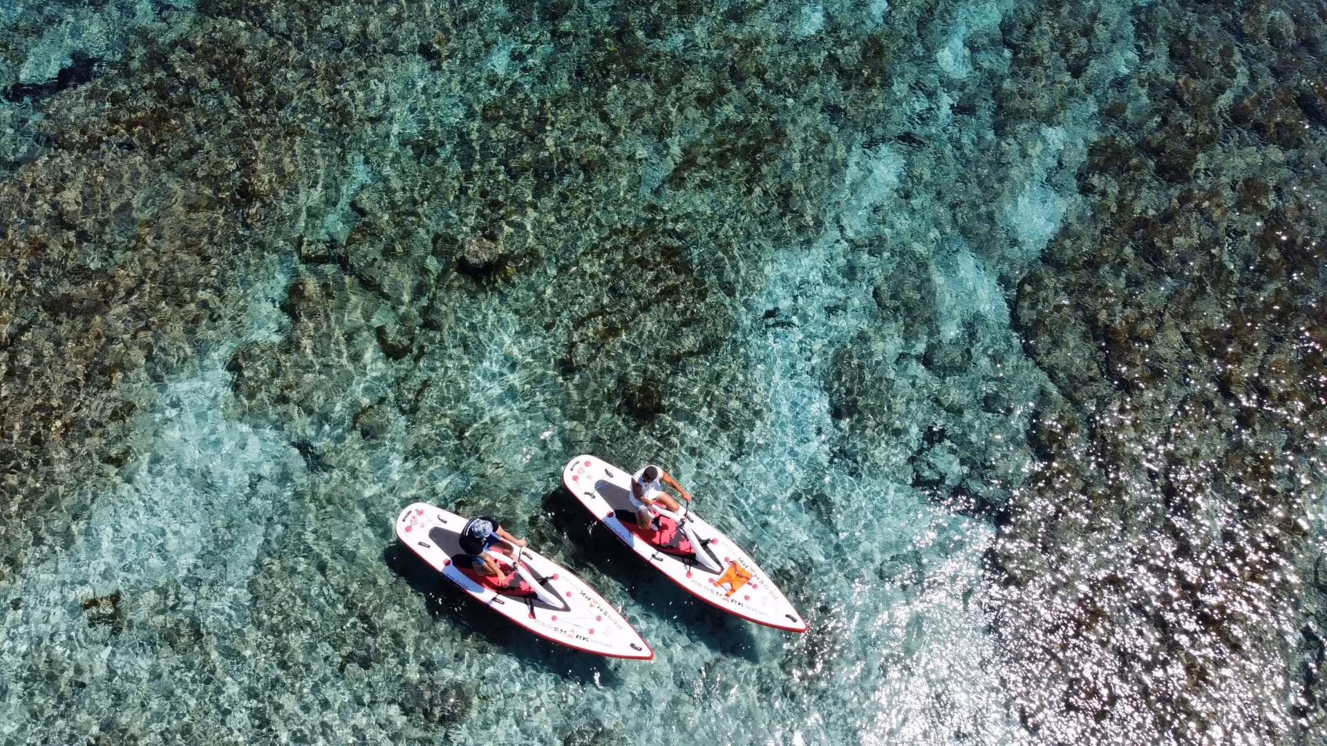 Two water bikes floating on the crystal-clear waters of Porto Torres, offering a unique perspective of the seafloor.