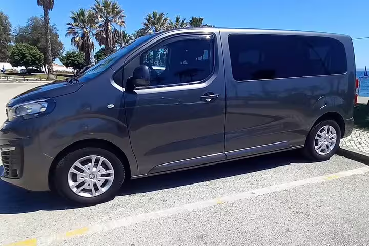 Comfortable tour van ready for 2-day Tomar-Coimbra and Fatima-Nazare-Obidos journey, parked under sunny skies.
