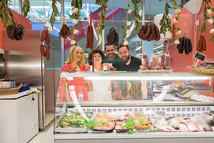 Friendly group at a traditional Porto deli counter showcasing cured meats and local specialties for an authentic culinary tour.