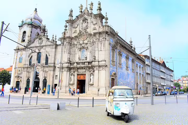 Tuk tuk parked in front of Porto's historic Carmo Church, offering guided tours of the city's iconic architectural landmarks.