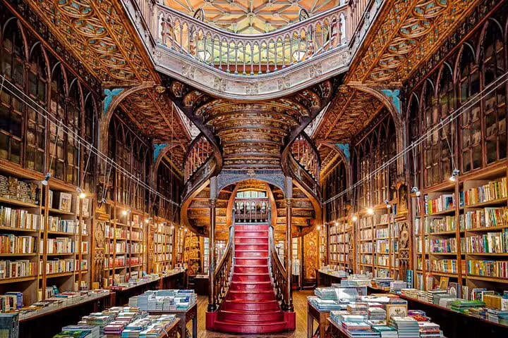 Ornate interior of Livraria Lello in Porto, featuring a grand red staircase, perfect for a cultural stop on a guided tuk tuk tour.