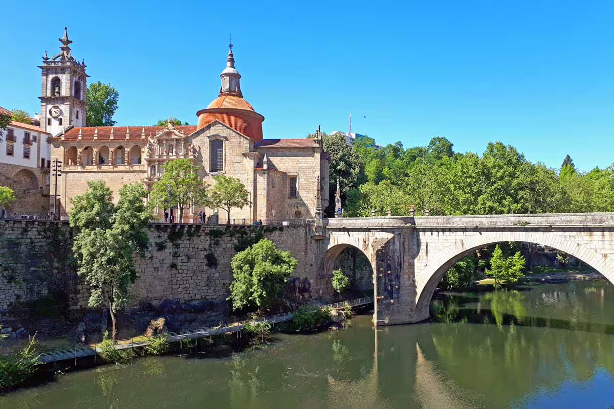 Scenic view of an ancient bridge and church surrounded by lush greenery on the Porto to Vieira do Minho route.