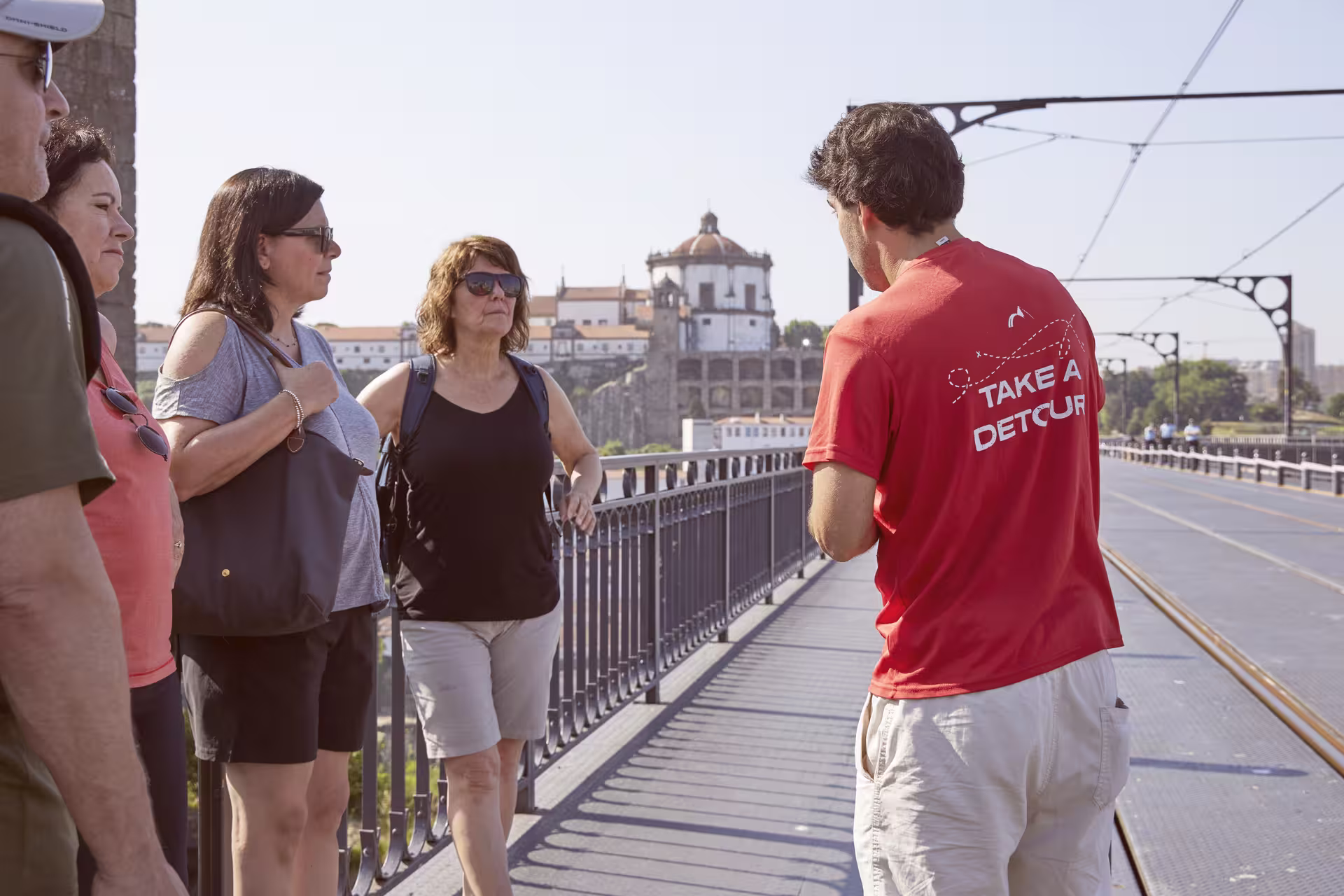 Tour guide leading a group on Porto's iconic bridge with scenic views of historic architecture.