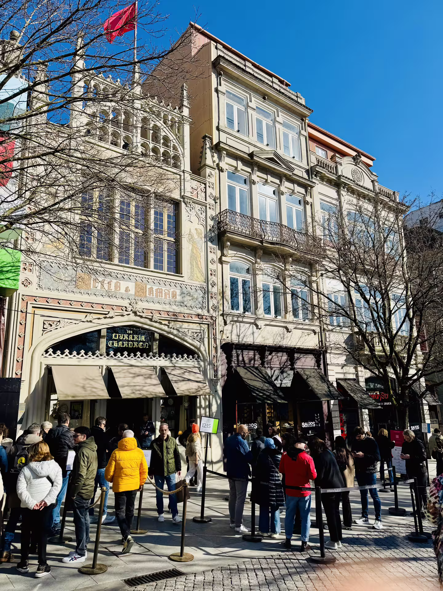 Tourists gather outside the historic Livraria Lello in Porto, a highlight of a small-group walking tour on a sunny day.