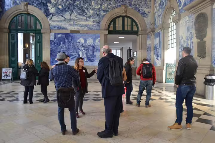 Visitors admire stunning azulejo tiles within São Bento Station, a must-see on the Essential Porto Walking Tour.