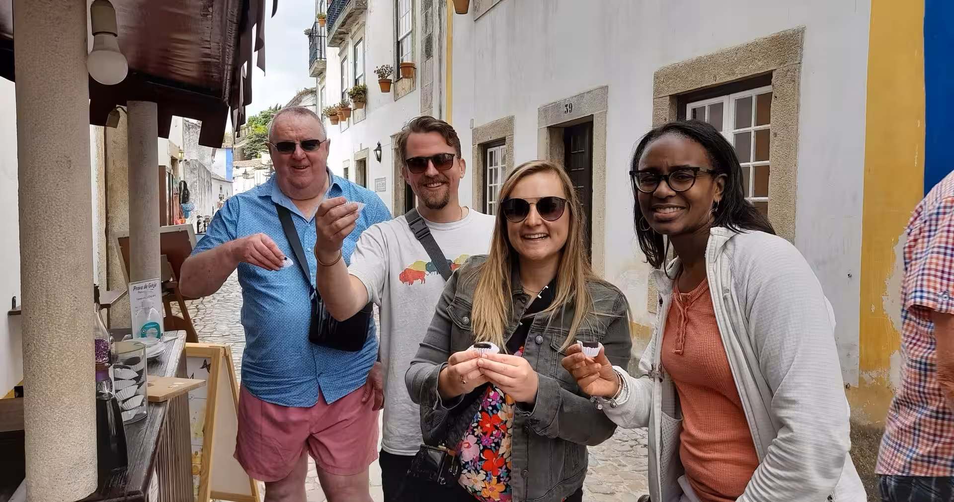 Travelers sample Portuguese liqueur in a charming village lane on an 8-day Portugal food and wine tour