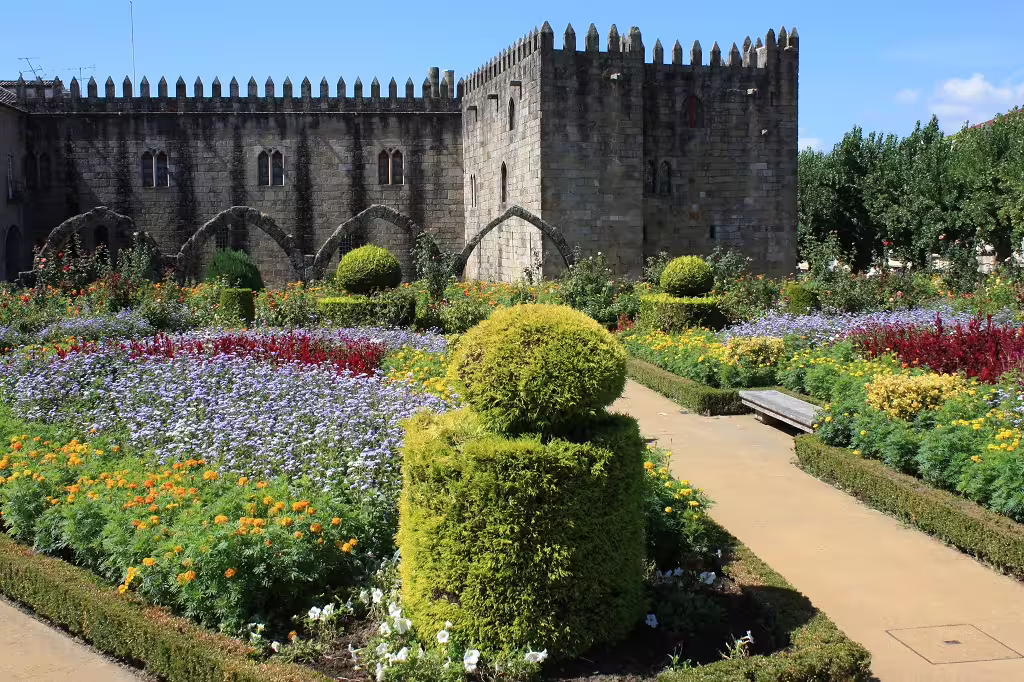 Historic medieval castle in Portugal surrounded by vibrant, colorful gardens, ideal for self-drive tours exploring North and South.
