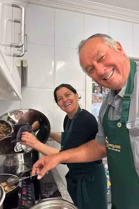 Smiling participants in a Portuguese cooking class joyfully preparing a dish in a modern kitchen setting.