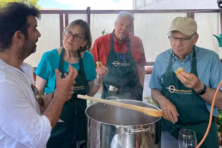 Participants engage in a hands-on Portuguese cooking class on a sunny terrace, learning traditional recipes.