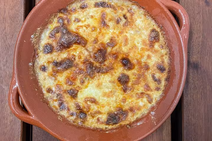 Golden-baked Portuguese dish in traditional clay pot, perfect for savoring on a scenic terrace during a cooking class.