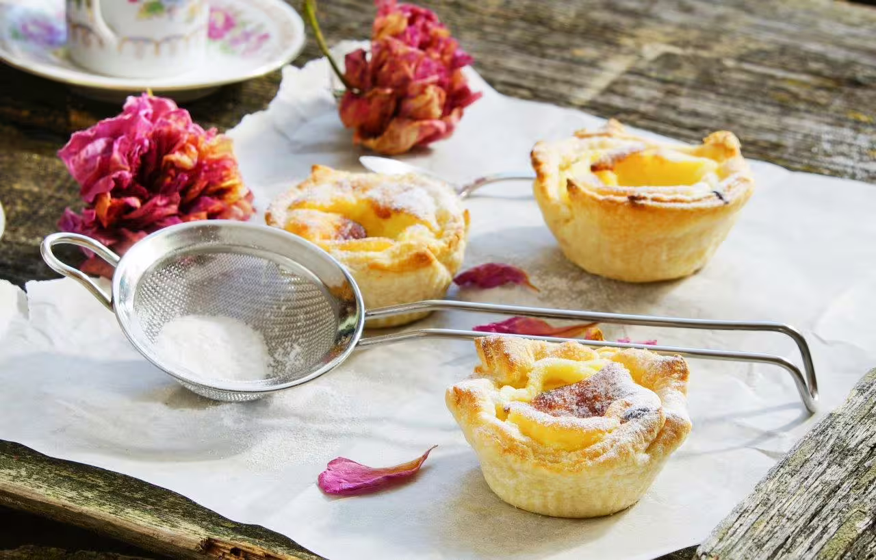 Delicious Portuguese custard tarts with powdered sugar and dried flowers, perfect for a culinary journey in Northern Portugal.