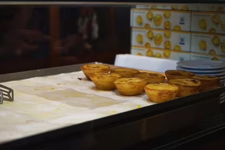 Freshly baked Portuguese custard tarts displayed on a tray, highlighting culinary delights on the tour.