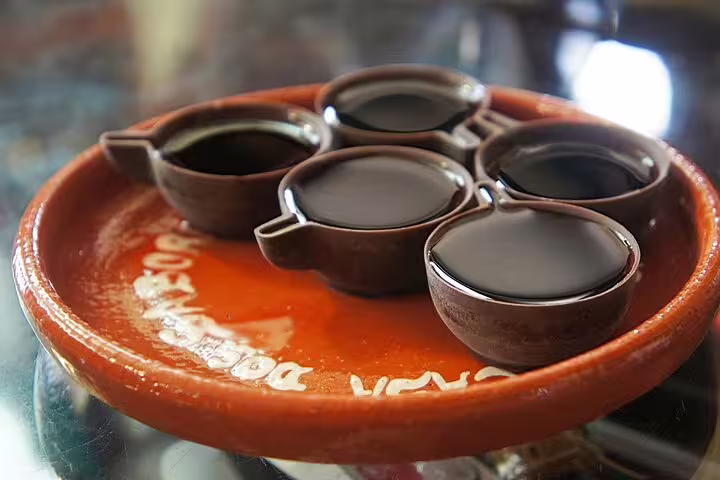 Traditional Portuguese ginjinha liqueur served in chocolate cups on a terracotta plate, a highlight of Obidos and Nazare tour.